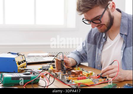 Man Working on Circuit Board With Tools and Equipment in Workshop Setting Stock Photo