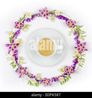 Cup of coffee with cream in a round vintage floral frame of jasmine flowers and wild flowers on a white background top view close-up Stock Photo