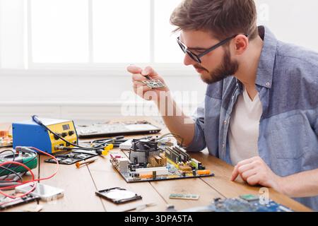 Technician Repairs Motherboard During Electronics Project in Workspace With Tools and Devices Stock Photo