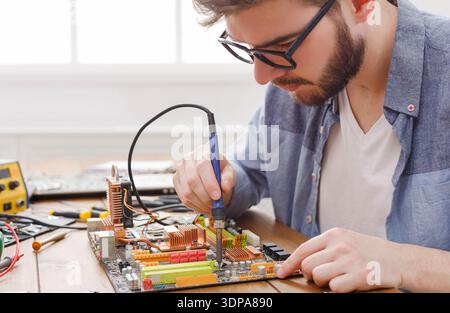 Technician Works on Motherboard in a Workspace to Fix Electronic Components and Conduct Repairs Stock Photo