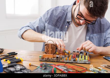 A Person is Working on a Computer Motherboard at a Wooden Table Stock Photo