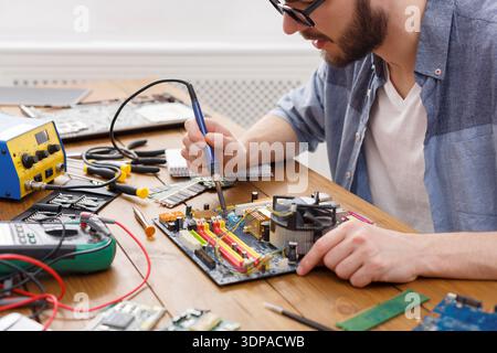 Technician Works on Computer Motherboard With Tools and Equipment at a Workbench Stock Photo