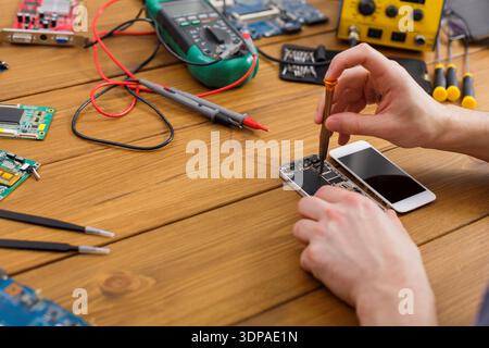 Repairing Mobile Phone With Tools and Parts on Wooden Table in Workshop Environment Stock Photo