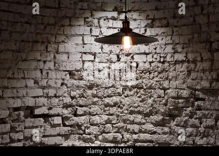 Unique Rustic Brick Wall With a Hanging Pendant Light in a Dimly Lit Room Stock Photo
