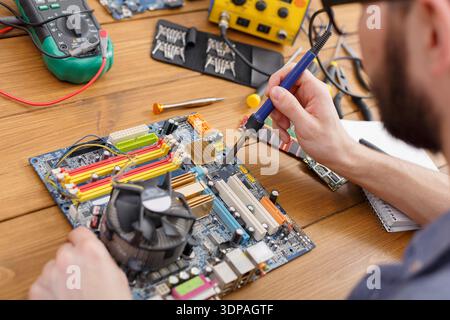 Expert Works on Electronic Circuit Board During a Repair Session in a Workshop Stock Photo
