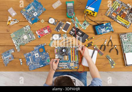 Repairing Electronics and Circuit Boards on a Wooden Table in a Workshop Setting Stock Photo