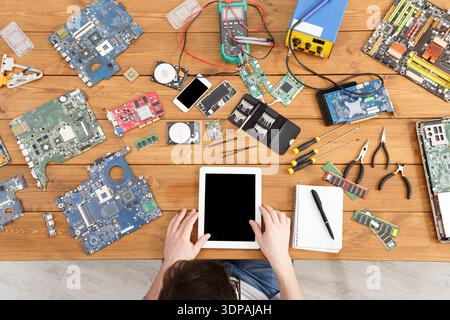 Person Works on Electronics With Tools and Devices on a Wooden Table Stock Photo