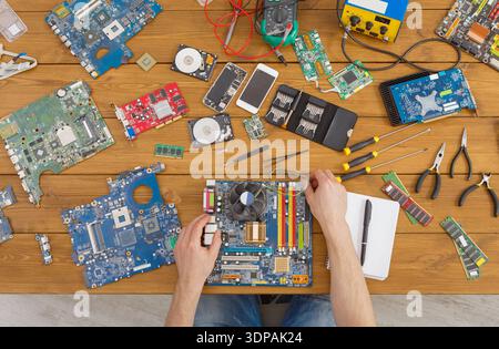 Repair Process of Computer Parts on a Wooden Table With Tools and Circuit Boards Present Stock Photo