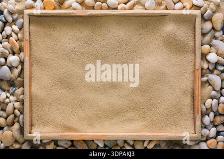 Beach sand in wooden tray on sea pebbles Stock Photo