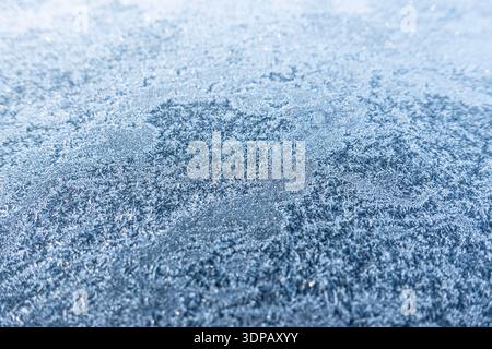Light blue frost crystals spread across a frozen surface, forming a delicate winter texture with subtle sparkle Stock Photo