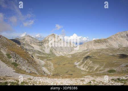Rugged mountain terrain with blue sky and clouds overhead, Italy Stock Photo