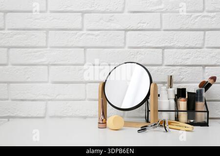Mirror, makeup brushes and different cosmetics on table in room Stock Photo