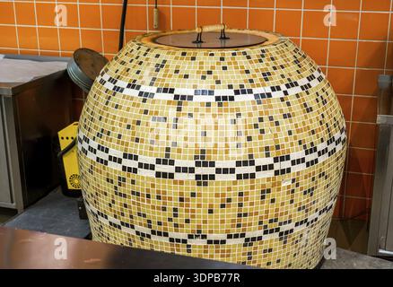 Large tandoor oven for making flat unleavened white bread in the form of a thin flatbread made of wheat flour. The furnace is in the shop Stock Photo