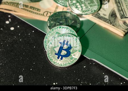 Laptop with bitcoins and dollar banknotes on black table, closeup Stock Photo