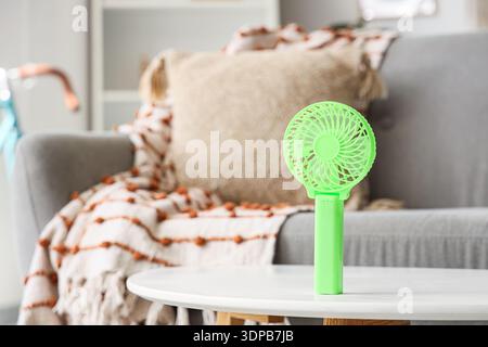 Green mini fan on table in living room, closeup Stock Photo