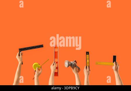 Many hands with measuring tools on orange background Stock Photo