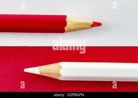Red and white color pencils on red and white background color papers arranged horizontally. Minimalist composition Stock Photo