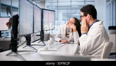 Doctors In Hospital Using Spreadsheets And Medical Codes, Feeling Stressed. Stock Photo