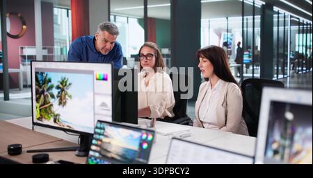 Creative Team Collaborates On Graphic Design Projects Using Desktop Computers Stock Photo