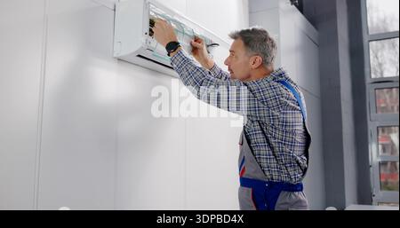 Professional HVAC Technician Performs Air Conditioner Cleaning And Filter Change. Stock Photo