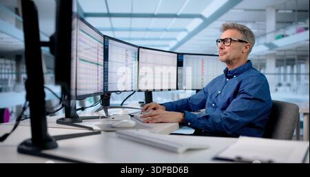 Male Office Manager Analyzing Multiple Business Monitors In Medical Office. Stock Photo