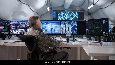 Modern Army Officer Uses Desktop Computer For Field Surveillance Operation Stock Photo