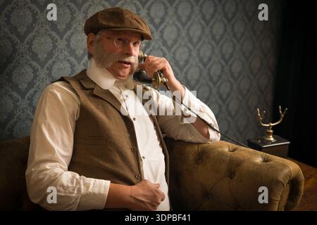 Lifestyle reenactment photo of a senior Victorian gentleman using an antique telephone Stock Photo