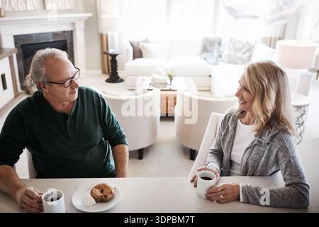 Talking, coffee and mature couple with breakfast in home with bonding, love and connection. Happy, conversation and man with woman for eating morning Stock Photo
