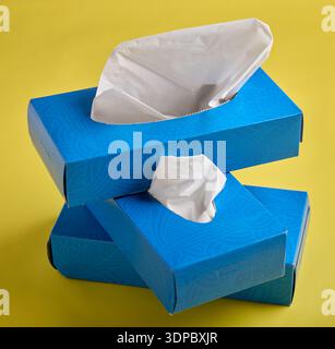 Stacked Blue Tissue Boxes on Bright Yellow Background Stock Photo