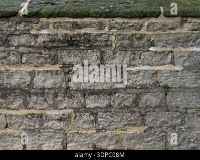 Old exterior stone wall with subtle mineral black staining. Stock Photo