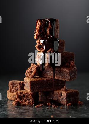 Brownie pieces on a black background. Melted chocolate drips down the brownie. Stock Photo