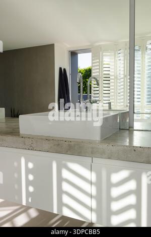 White rectangular vessel sink is sitting on concrete countertop at vanity, chrome faucet shining Stock Photo