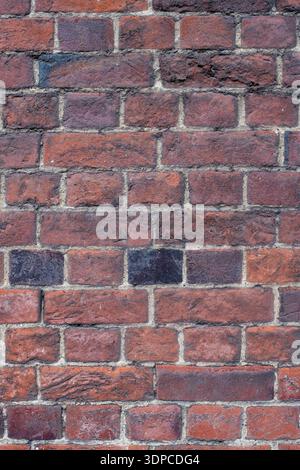 Weathered Victorian red brick wall with dark blue glazed header bricks creating decorative pattern, showing aged mortar and texture Stock Photo