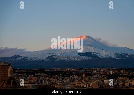 Snowy Mount Etna illuminated by sunset light, viewed from Catania in Sicily, Italy Stock Photo