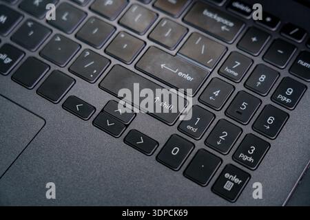 A close-up shows a laptop keyboard with focus on the enter and shift keys while someone types on the device. Stock Photo