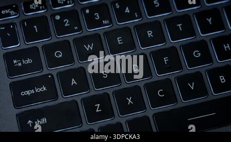 The picture shows a close view of a laptop keyboard in a home office setting during the day. Keys are visible with letters and numbers. Stock Photo
