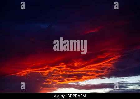 Intense red and orange sunset clouds burning through a dark dramatic sky Stock Photo