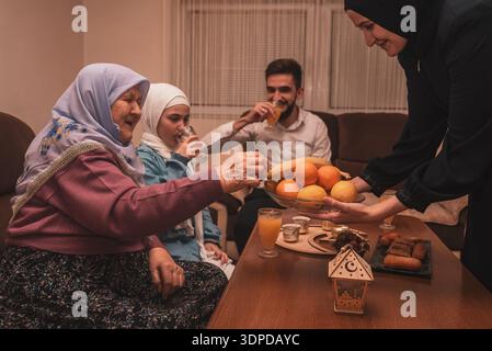 Happy Muslim family having iftar dinner during Ramadan dining table at home, sharing food and smiling together. Stock Photo