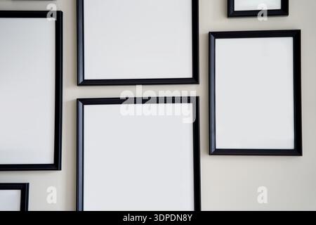 Different size framed photos hanging on the gray wall. Mockup. Stock Photo