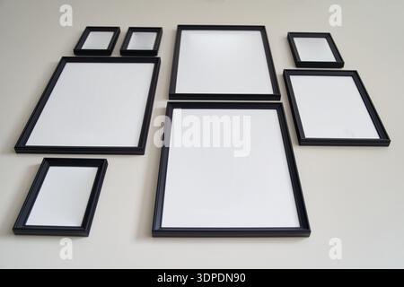 Different size framed photos hanging on the gray wall. Mockup. Stock Photo