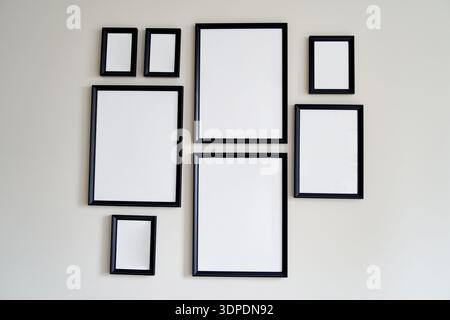 Different size framed photos hanging on the gray wall. Mockup. Stock Photo