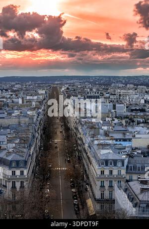 2026 Paris.Sunset over Paris: a high-angle view of a straight street with classic architecture under a dramatic orange sky with heavy clouds. Stock Photo