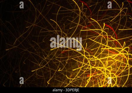Macro abstract golden light streaks and sparks forming chaotic glowing pattern. Dark background with copy space, long exposure Stock Photo