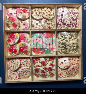 Assortment of charming vintage wooden buttons in a wooden tray featuring romantic floral patterns, roses, daisies and botanical motifs Stock Photo
