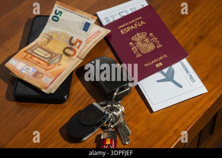 Spain passport, boarding pass, Euro money, car keys, and smartphone on wooden table Stock Photo
