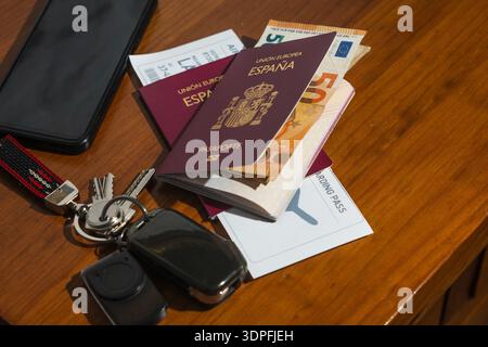Spanish passport, euro currency, boarding pass, smartphone, and keys on wooden surface Stock Photo