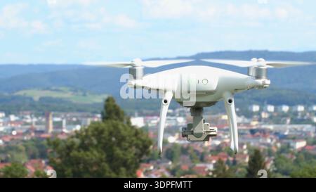 Drone flies over a city with mountains in the background on a clear day Stock Photo