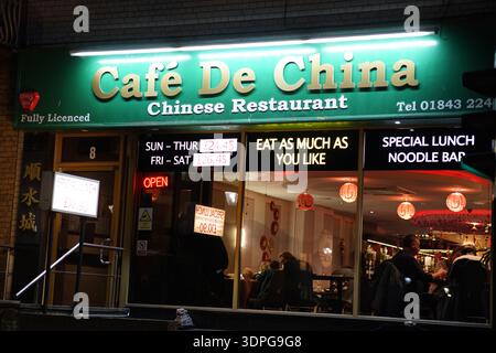 Café De China restaurant in Margate at night, green illuminated sign offering all-you-can-eat and noodle bar, warm interior lights, Kent England Stock Photo