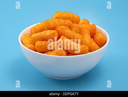 Crispy corn sticks in white bowl isolated on blue background Stock Photo