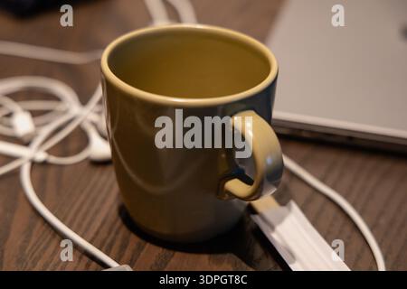Olive Ceramic Mug Beside Laptop Cables Stock Photo